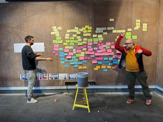 Zwei Personen vor einer grossen Wand mit vielen bunten Post-Its.
